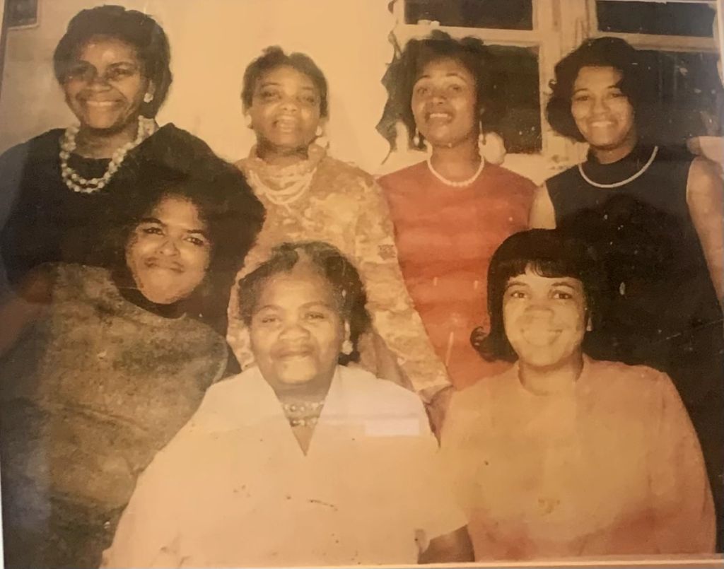 Faded sepia photo of eight women in a family group, original