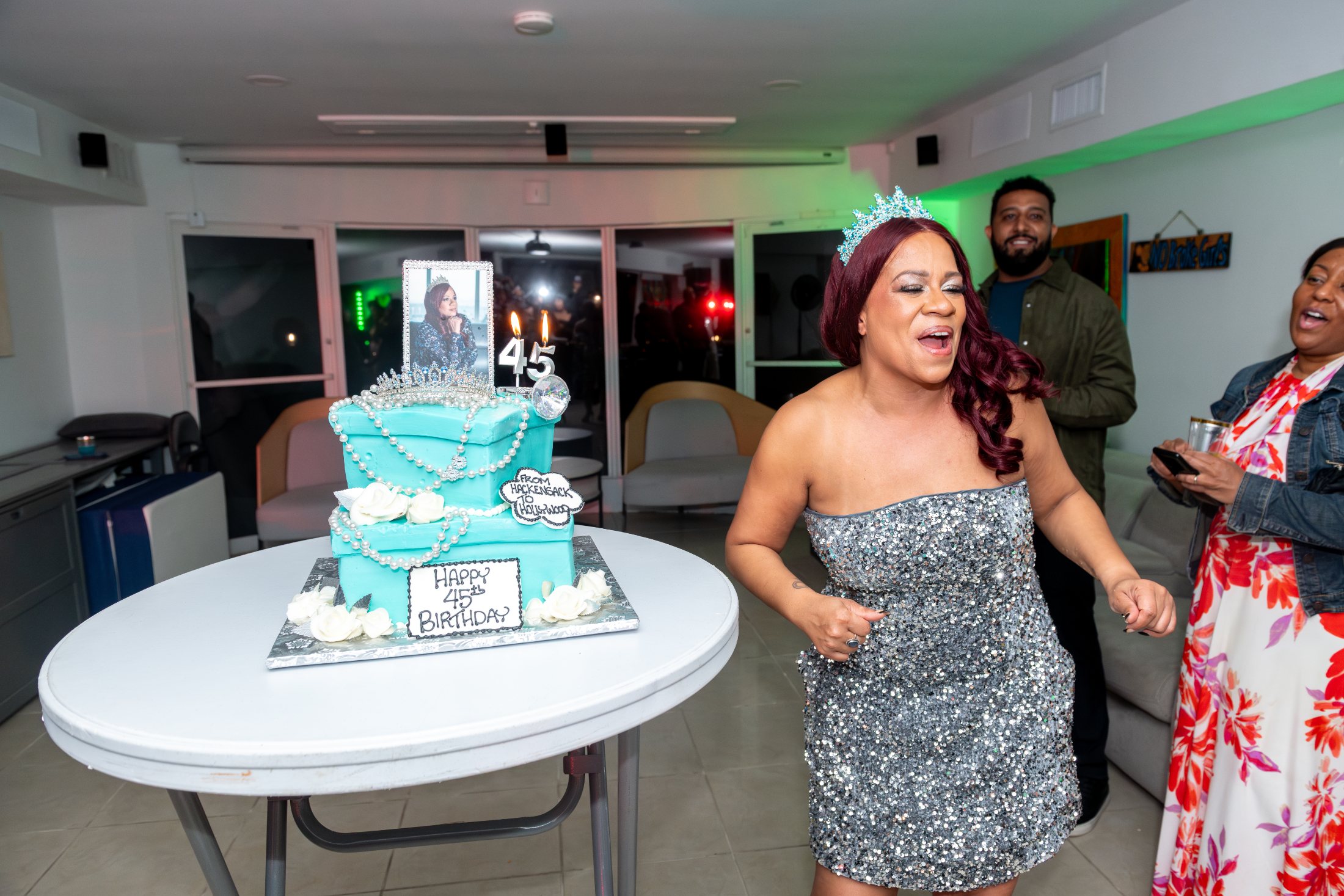 Birthday celebration with the guest of honor beside a tiered cake