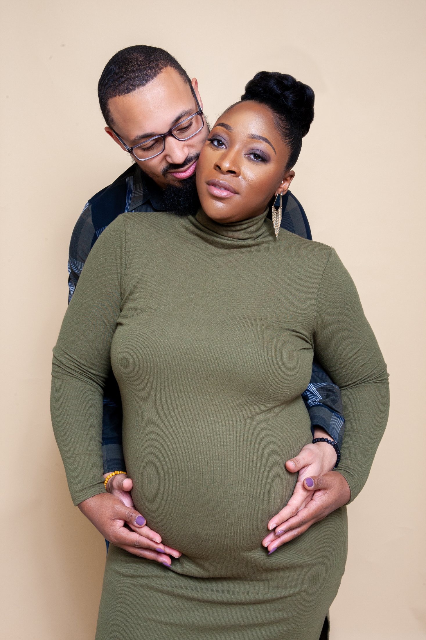 Maternity portrait of a couple, she in a fitted green dress