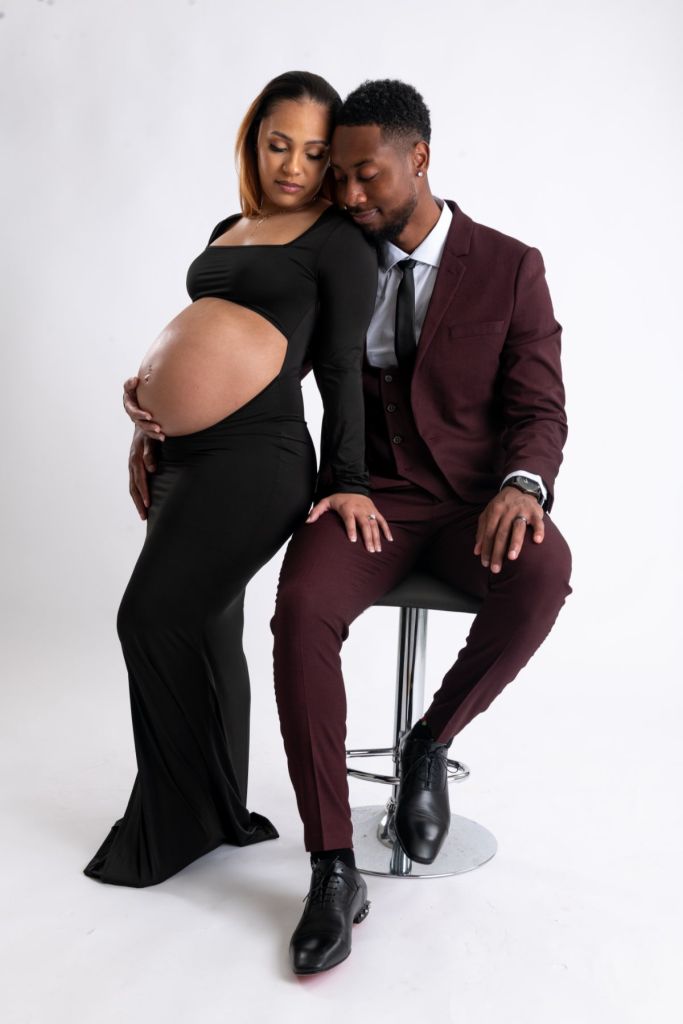 Maternity portrait of an expecting couple, he in a burgundy suit