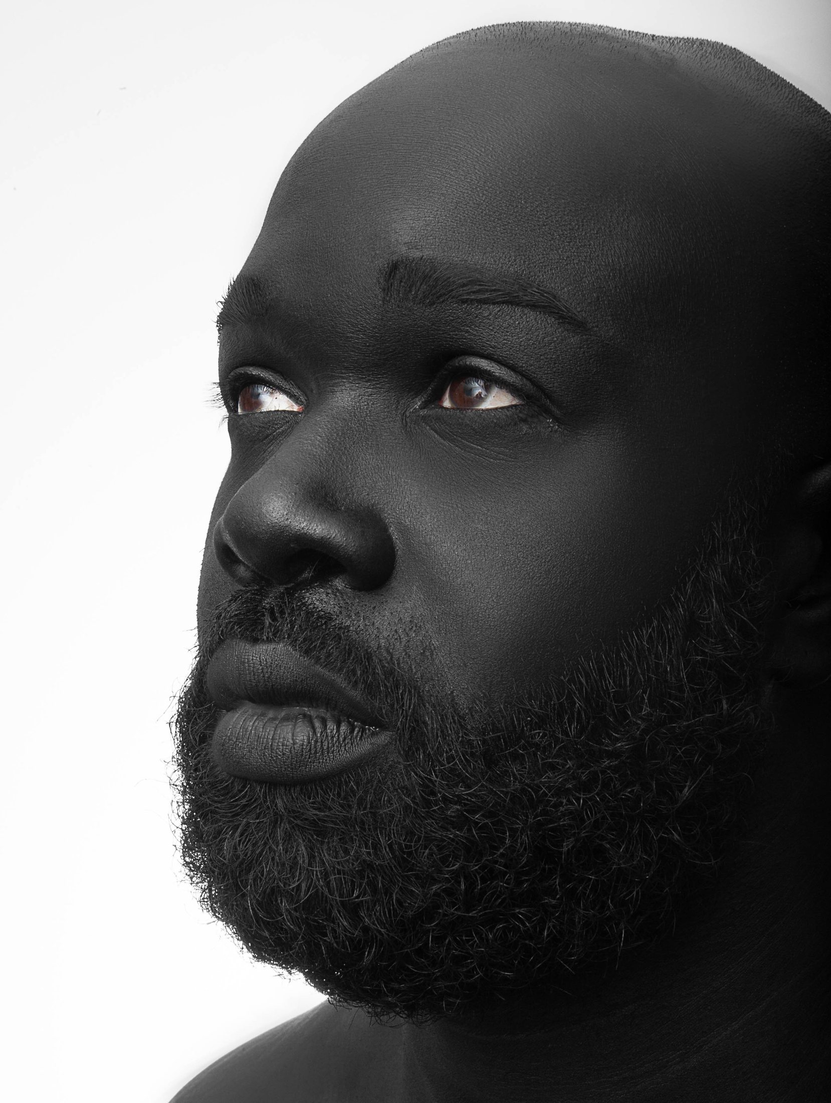 Black-and-white portrait of a bearded man looking up in dramatic side light
