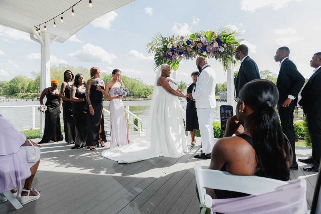 Wedding ceremony by the water under a floral arch