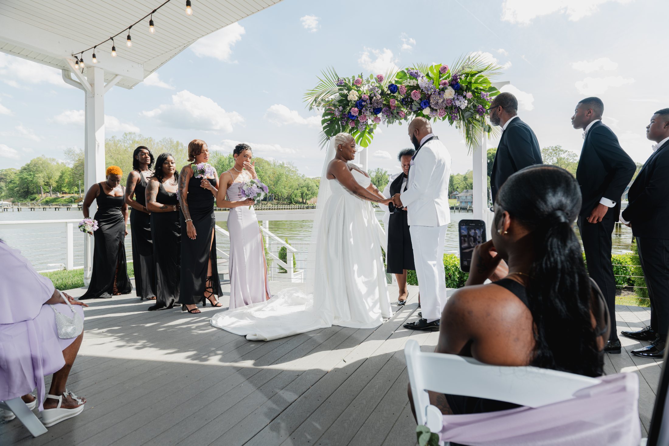 Wedding ceremony by the water under a floral arch
