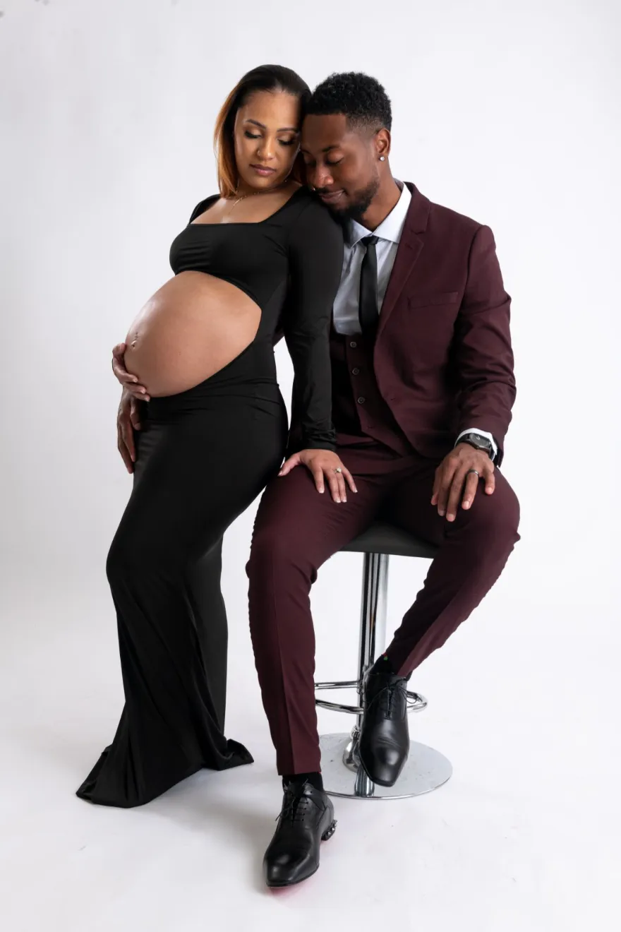Maternity portrait of an expecting couple, he in a burgundy suit